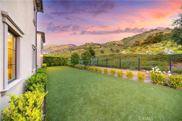 yard at dusk with a fenced backyard and a mountain view