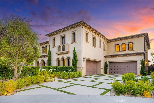 view of front of home featuring an attached garage, driveway, and a balcony