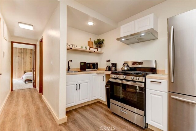 1288 Clubview Dr, Big Bear Lake, CA 92315 - kitchen with under cabinet range hood, appliances with stainless steel finishes, light wood finished floors, and a sink
