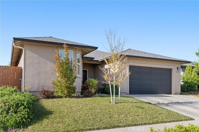 view of front of home with a front yard, stucco siding, driveway, an attached garage, and fence