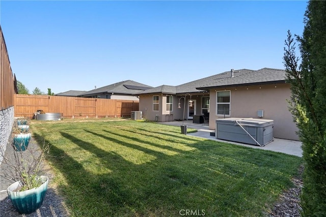 back of house featuring a fenced backyard, a patio area, stucco siding, and a hot tub