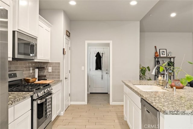 kitchen with recessed lighting, a sink, stainless steel appliances, tasteful backsplash, and white cabinetry