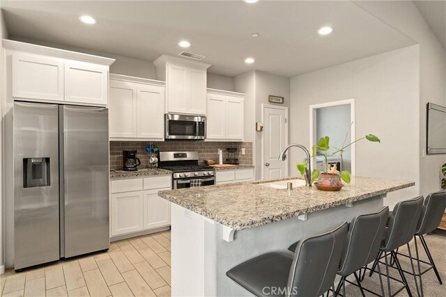 2958 Beaumont Ave, Chico, CA 95928 - kitchen featuring a sink, white cabinetry, backsplash, a center island with sink, and appliances with stainless steel finishes