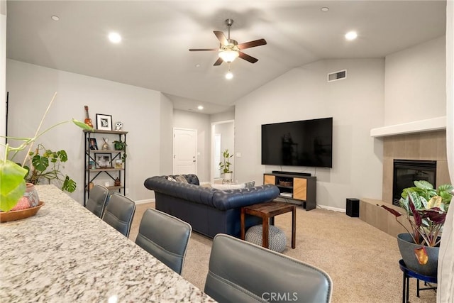 living room with carpet, vaulted ceiling, a fireplace, visible vents, and a ceiling fan