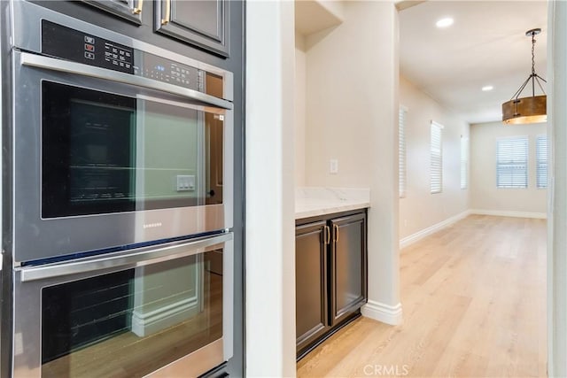 33827 Flora Springs St, Temecula, CA 92592 - kitchen featuring double oven, light wood finished floors, light stone countertops, decorative light fixtures, and recessed lighting
