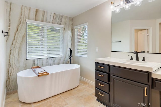 full bathroom with a freestanding tub, vanity, and baseboards