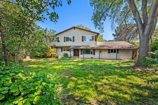 view of front of home featuring a front yard, a patio, and stucco siding