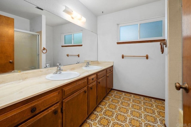 bathroom featuring double vanity, toilet, a shower stall, and a sink