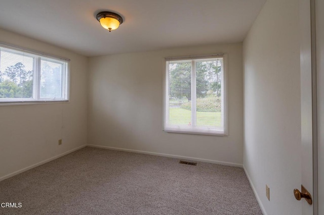 carpeted spare room featuring visible vents and baseboards