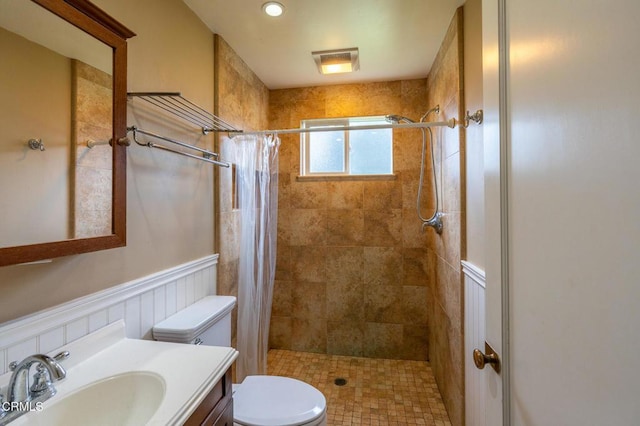 bathroom featuring toilet, a stall shower, wainscoting, and vanity