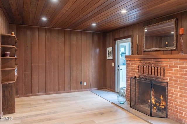 unfurnished living room with a fireplace, wooden walls, wood finished floors, and wood ceiling