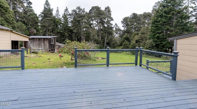 wooden deck with a lawn, a storage unit, and an outbuilding