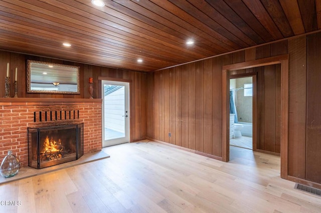 unfurnished living room with wood ceiling, wood finished floors, wood walls, and a fireplace