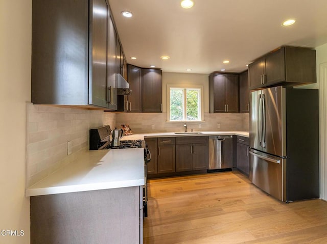 kitchen featuring appliances with stainless steel finishes, tasteful backsplash, light countertops, and light wood-style flooring
