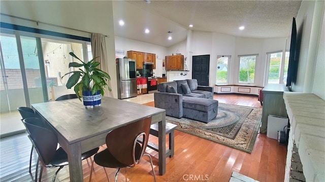 dining area featuring lofted ceiling, a textured ceiling, recessed lighting, and light wood-style floors
