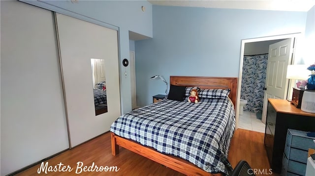 bedroom with ensuite bathroom, a closet, and wood finished floors