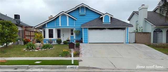 view of front of property with an attached garage, fence, a shingled roof, a front yard, and driveway
