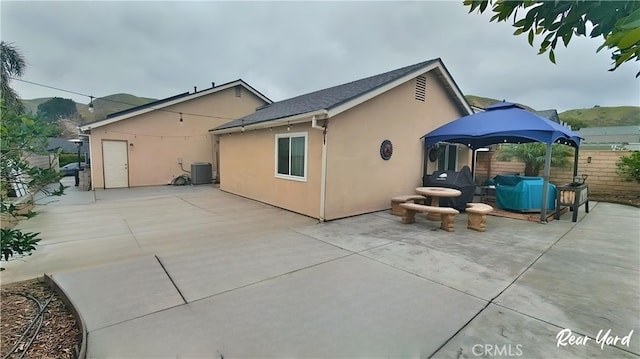 rear view of property featuring central AC unit, fence, a patio, and stucco siding