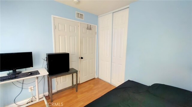 bedroom with a closet, light wood-type flooring, and visible vents