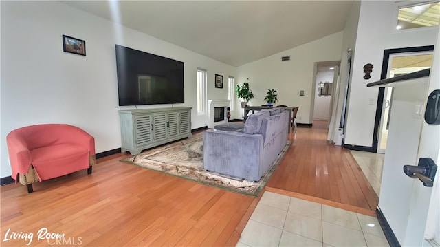 living area featuring visible vents, baseboards, lofted ceiling, and wood-type flooring