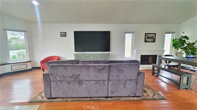 living room featuring a fireplace, a textured ceiling, and wood finished floors
