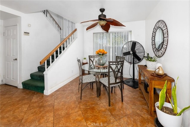 tiled dining space with ceiling fan, stairway, and baseboards