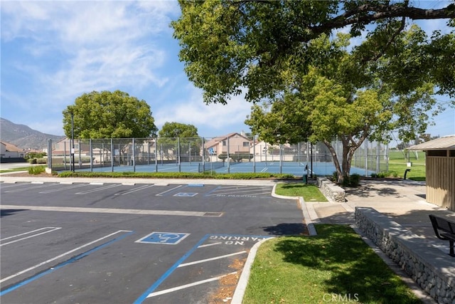 uncovered parking lot with a tennis court and fence