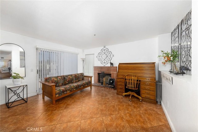 tiled living room featuring baseboards and a brick fireplace