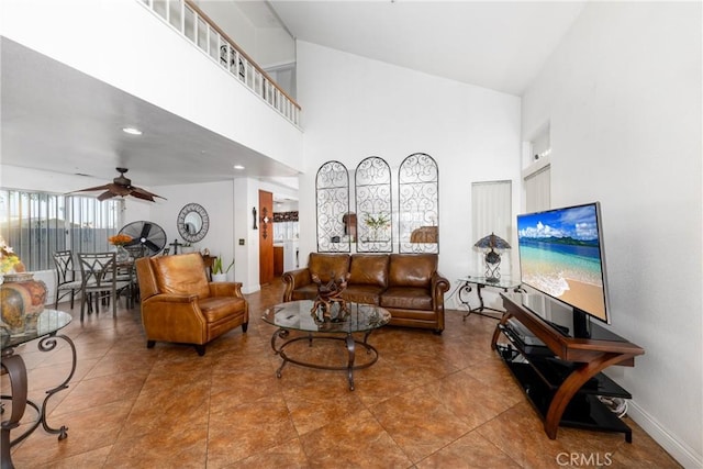 tiled living area with ceiling fan and a high ceiling
