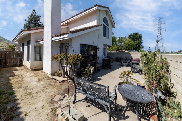 rear view of house with a tile roof, a patio, stucco siding, and a fenced backyard