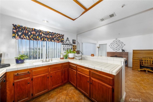 kitchen with a sink, visible vents, light countertops, dishwasher, and tile patterned flooring