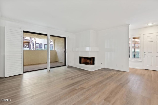 unfurnished living room featuring crown molding, baseboards, wood finished floors, and a fireplace