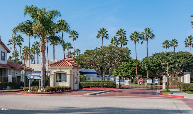 view of road featuring a gated entry, sidewalks, a gate, curbs, and traffic signs