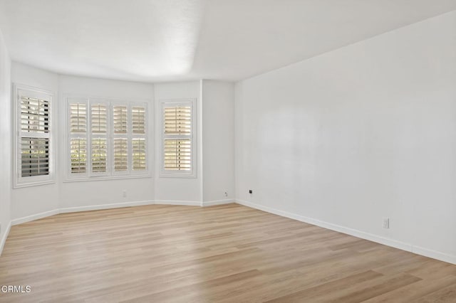 unfurnished room featuring baseboards and light wood-type flooring