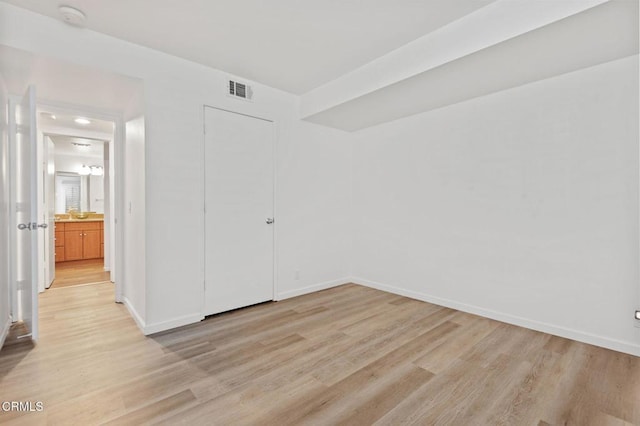 unfurnished bedroom with a closet, visible vents, light wood-style flooring, and baseboards