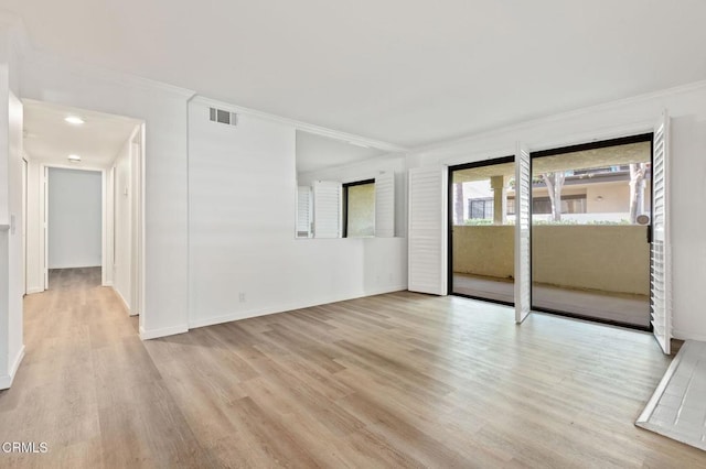 spare room featuring wood finished floors, visible vents, crown molding, and baseboards