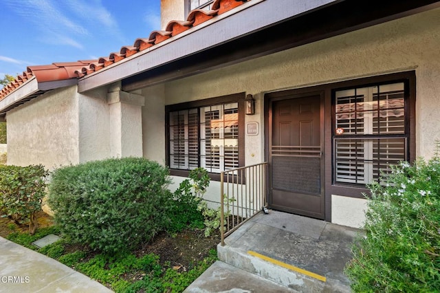 property entrance featuring a porch, stucco siding, and a tiled roof