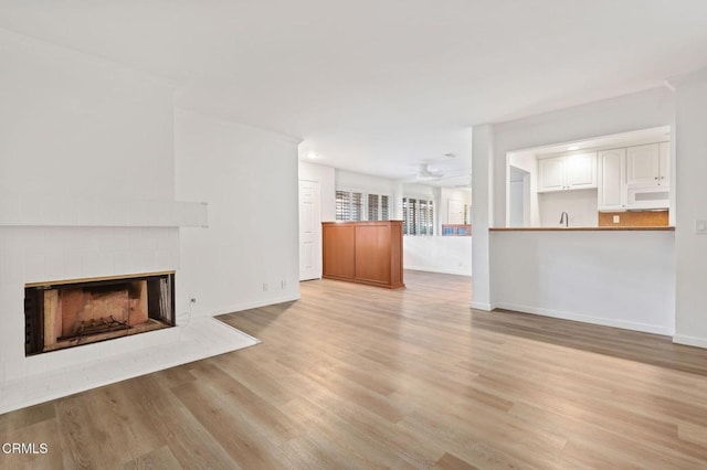 unfurnished living room with baseboards, light wood-style floors, and a fireplace