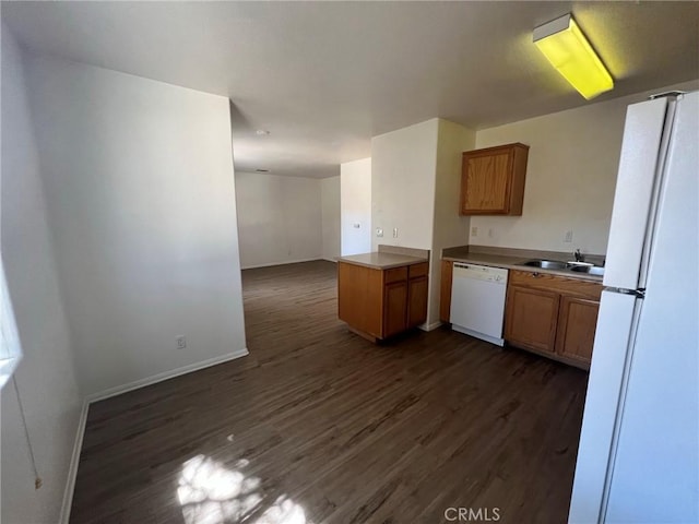 6476 Desert Knoll Ave Unit 29, Palms, CA 92277 - kitchen with white appliances, brown cabinets, a sink, baseboards, and dark wood-type flooring