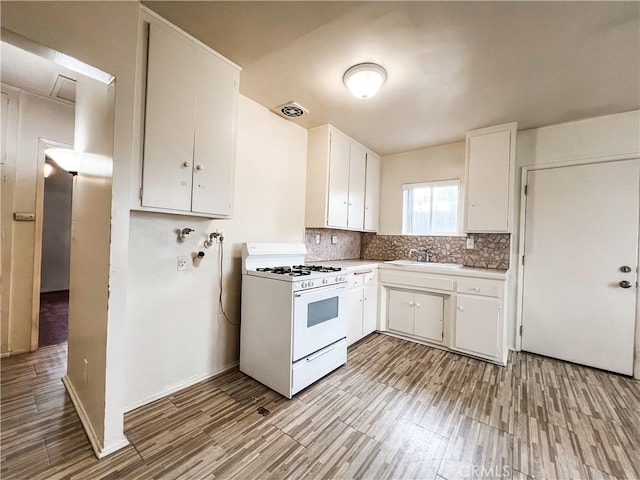 kitchen with a sink, white range with gas cooktop, white cabinets, and light wood-style flooring
