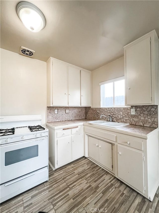 kitchen featuring light countertops, light wood finished floors, white range with gas stovetop, and white cabinetry