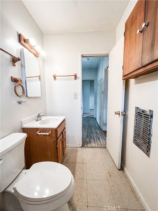 half bath with toilet, baseboards, and vanity