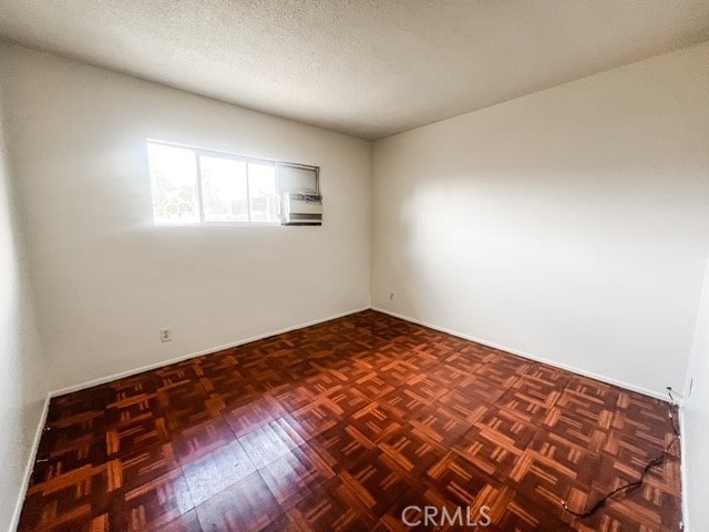 spare room featuring a textured ceiling and baseboards
