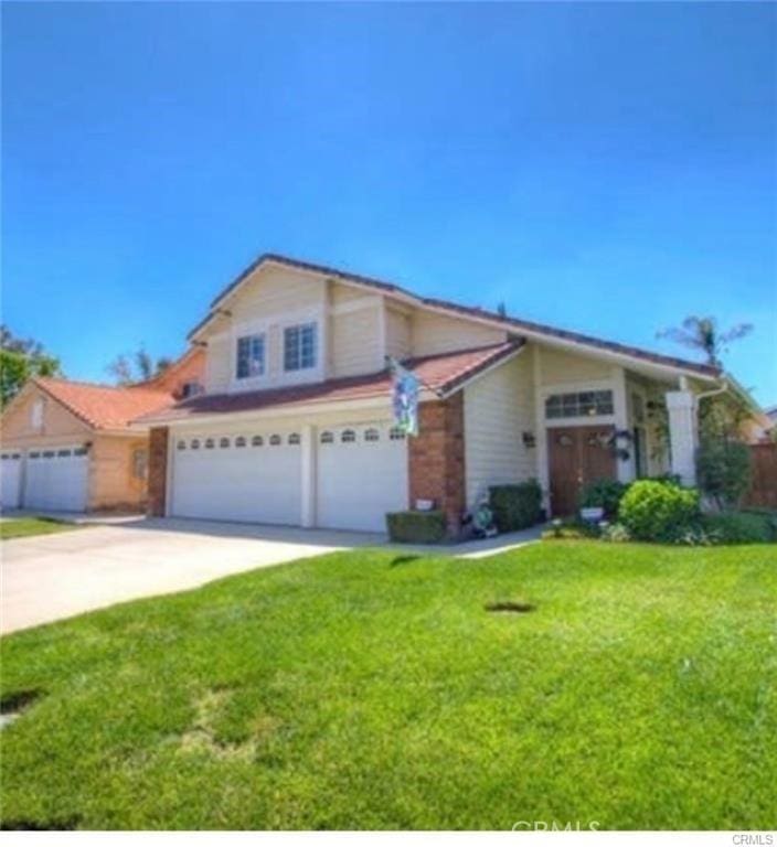 view of front of home with an attached garage, a front lawn, and concrete driveway