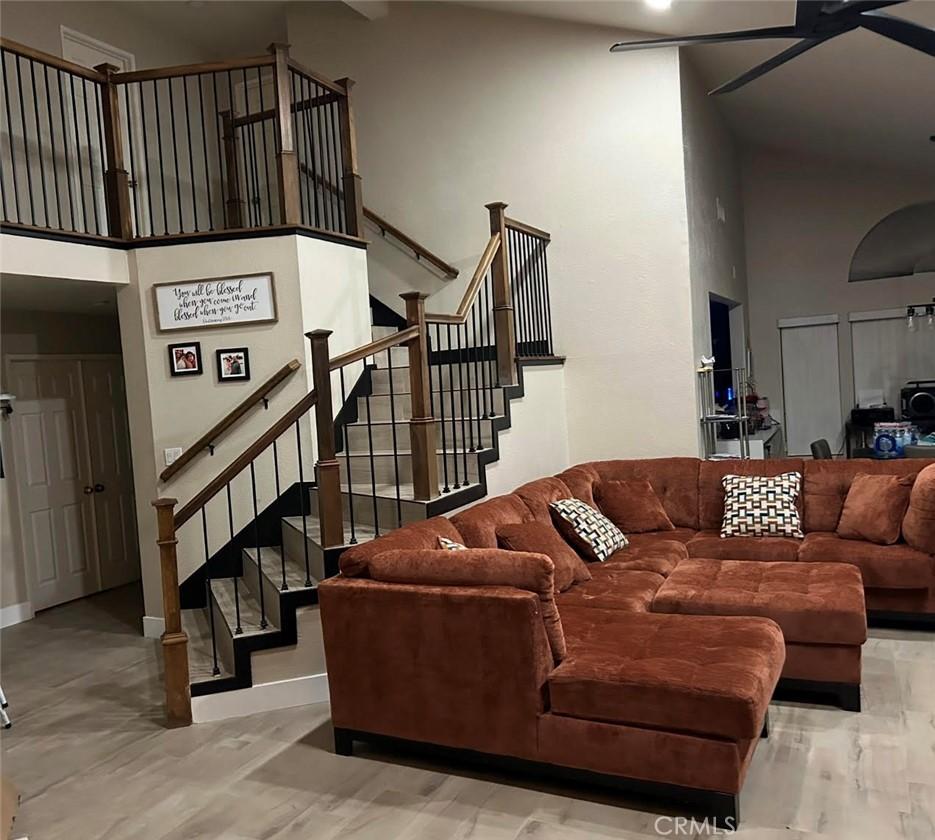 living area featuring stairs, a high ceiling, and ceiling fan