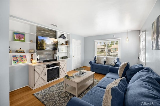 living area featuring a glass covered fireplace and light wood-style floors