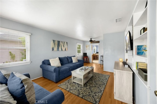 living room with a ceiling fan, visible vents, and wood finished floors