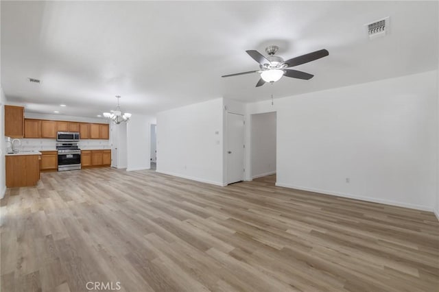 unfurnished living room featuring visible vents, light wood-style floors, ceiling fan with notable chandelier, and baseboards