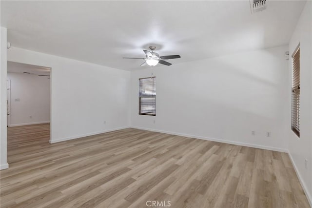 empty room featuring a ceiling fan, visible vents, baseboards, and light wood-style floors