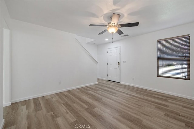 unfurnished living room featuring visible vents, light wood-type flooring, a ceiling fan, and baseboards